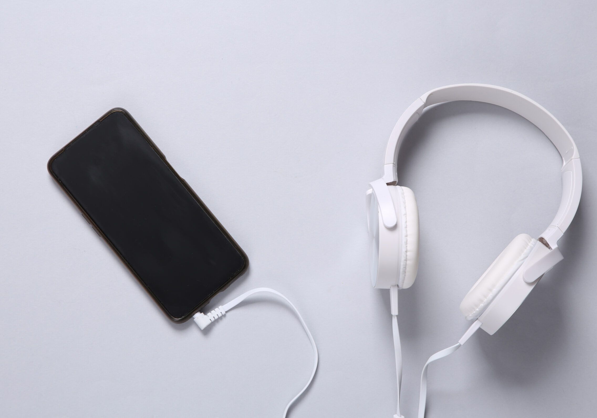 Stereo headphones connected to smartphone on gray background
